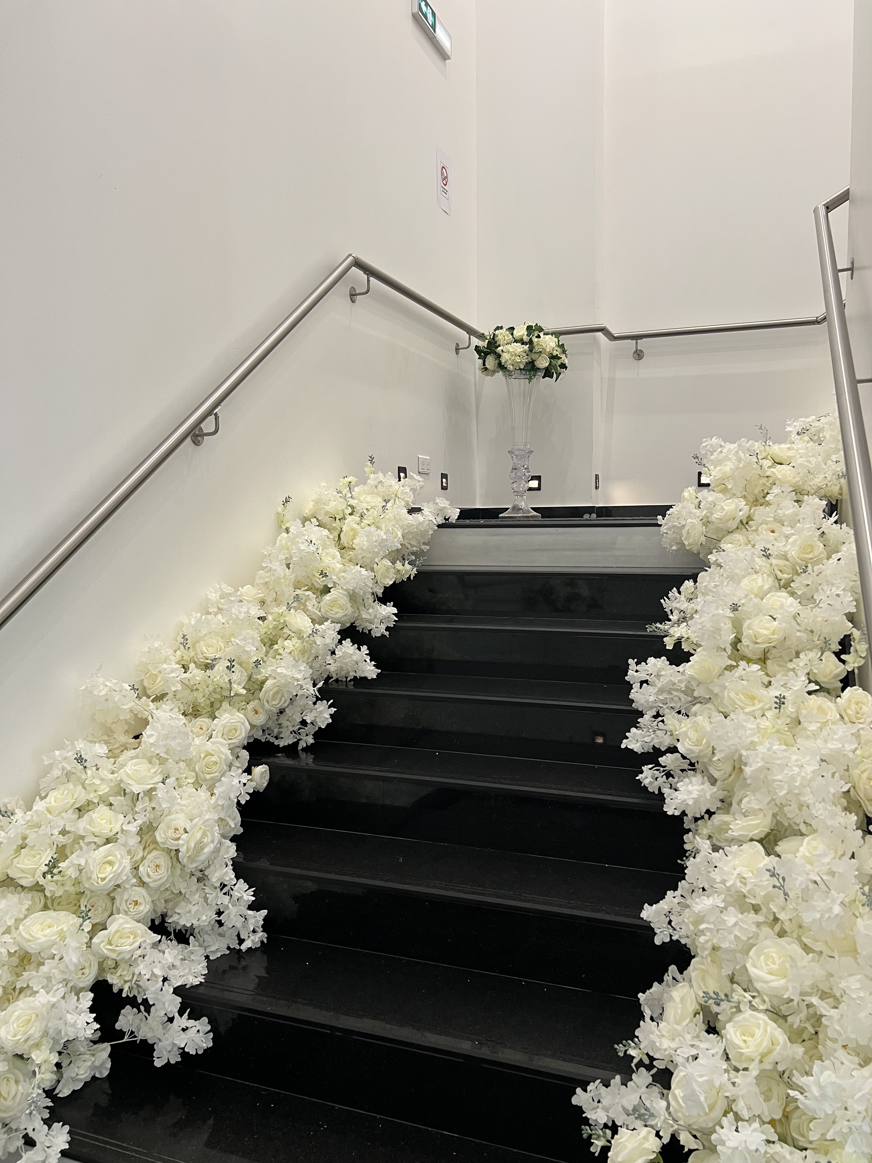 Escalier d'honneur du Palace Victory Events bordé de roses blanches avec lustre en cristal